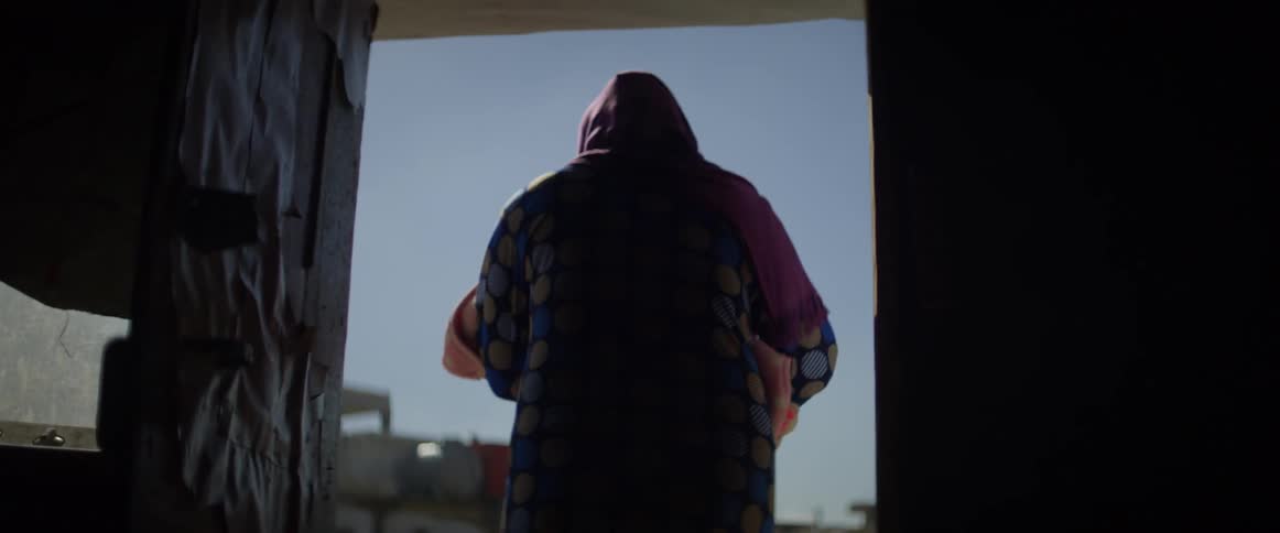 Person opens a door and walks out into a village on a sunny day