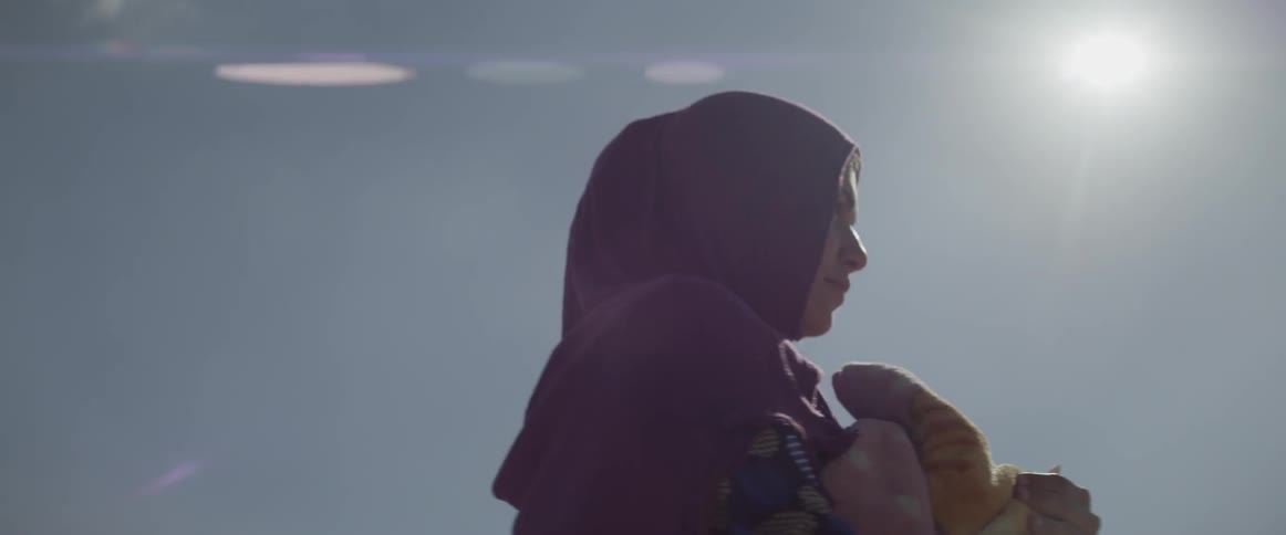 A woman wearing a headscarf walks on a sunny day