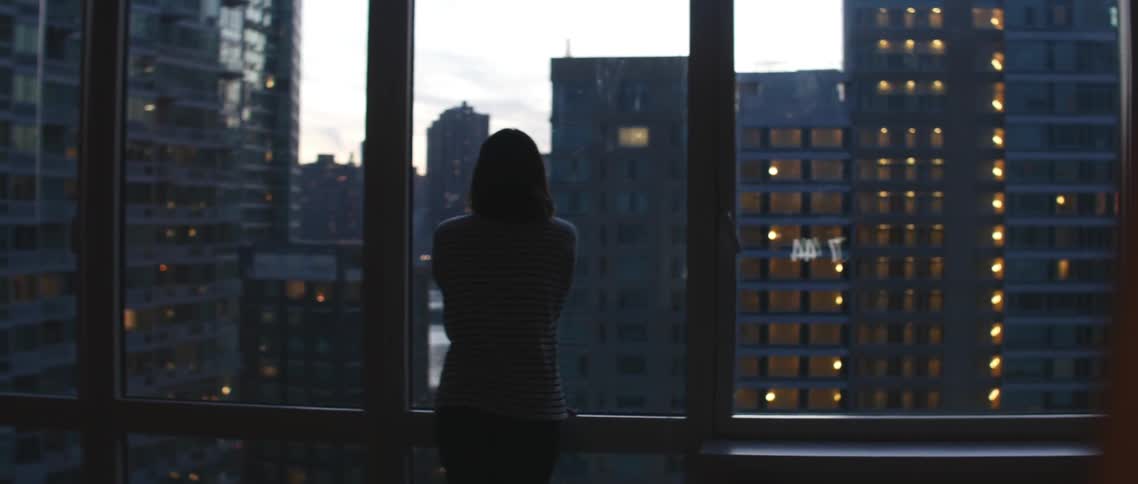 Woman standing by a window looking over a city