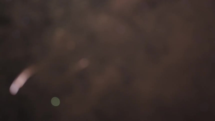 Fireworks exploding in night sky giving off smoke