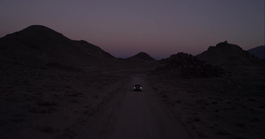 A car driving down a rural road at dusk