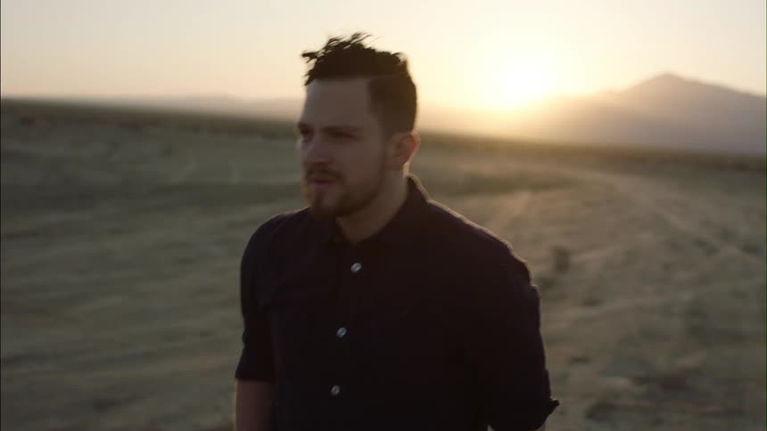 Man walking down a large empty field at sunrise