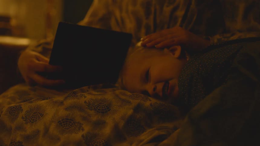 A woman runs the head of a child on her lap