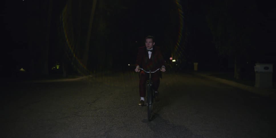 A boy in a tuxedo rides a bike