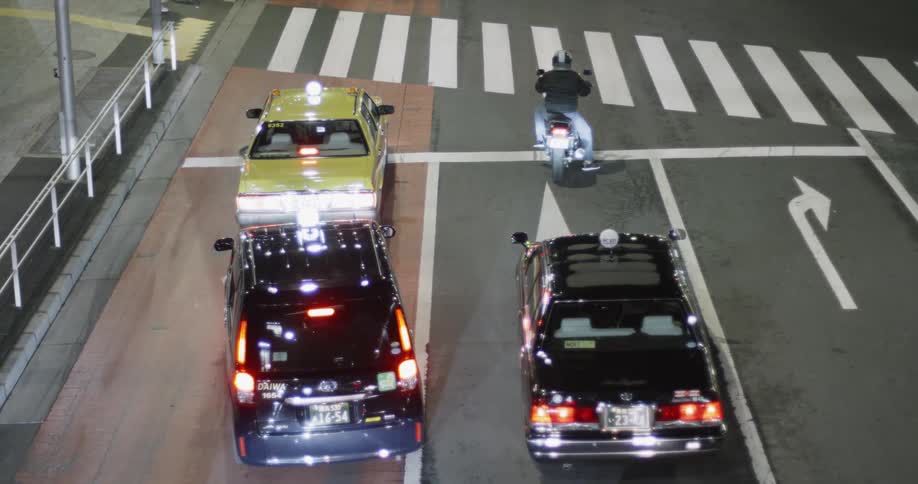 Cars and a motorcycle sit at a stoplight