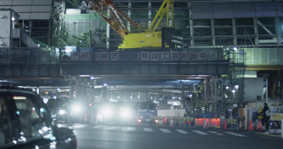 Vehicles drive through an industrial area at night