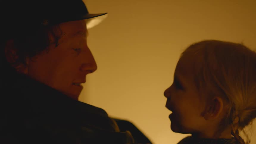 Man talks to a child in dim light