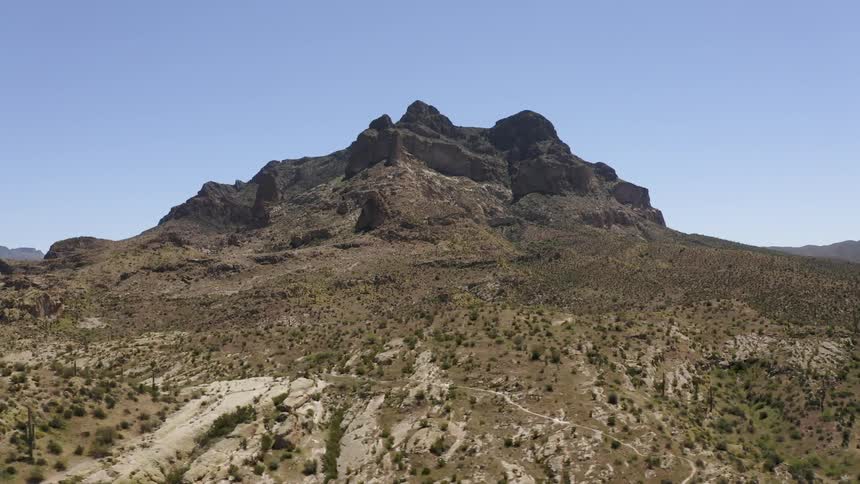Cactus and brush on hills leading up to a rocky peak