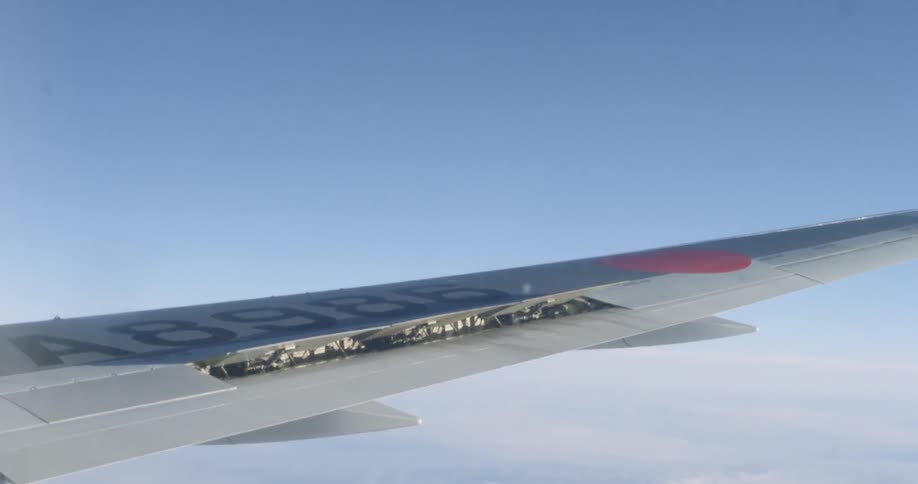 Airplane wing flies over the clouds under a blue sky