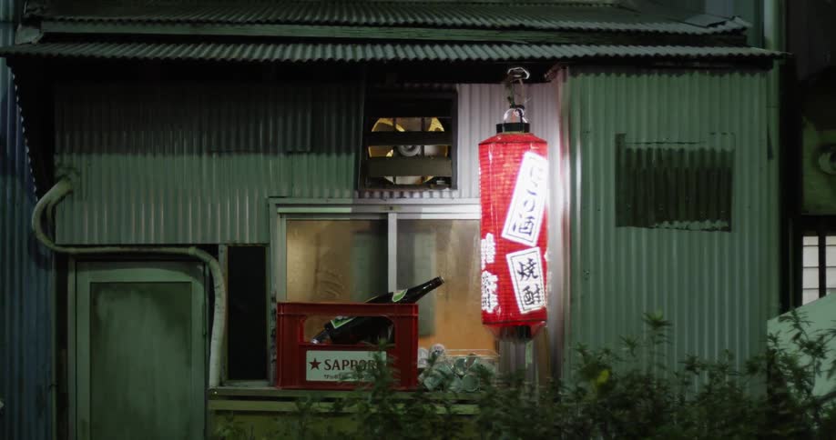A hanging light illuminates outside of a shack building