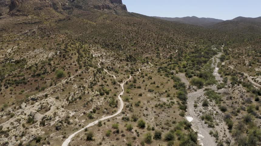 A person is hiking on a trail in a desert landscape on a sunny day