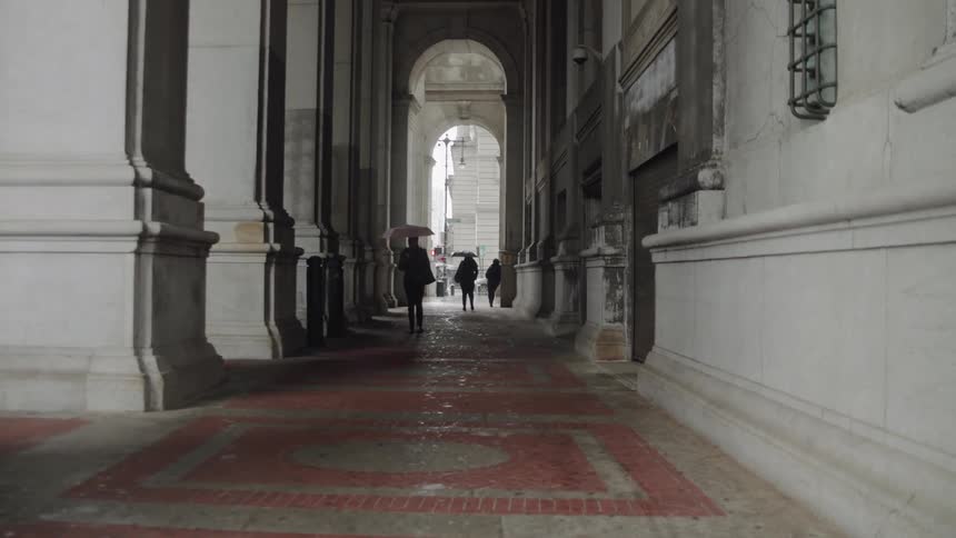 People walk past the building under the arches