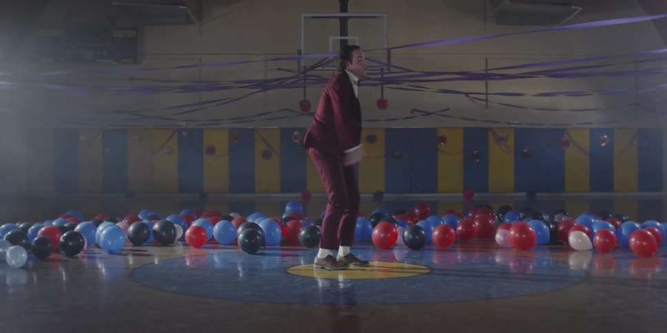 Man in red suit breakdances in a gymnasium