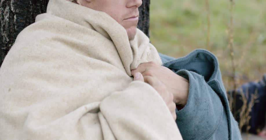 A soldier covers up with a blanket