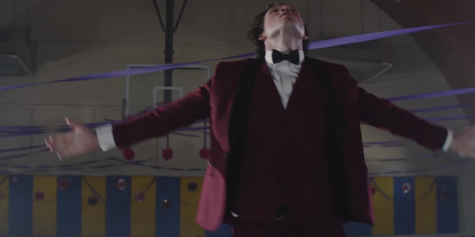 A teenager is dancing in a red tuxedo