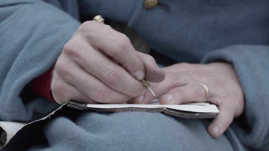 A man writes in a journal while sitting outside
