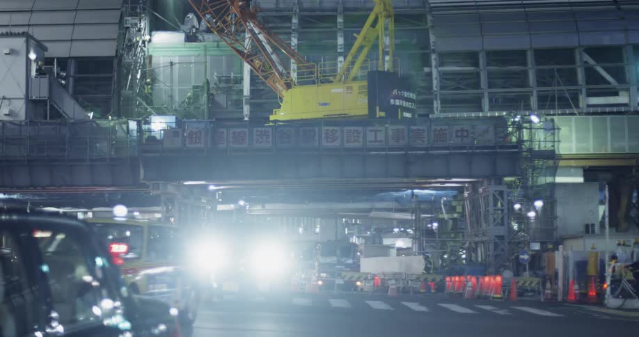 The cars drive through the intersection at night