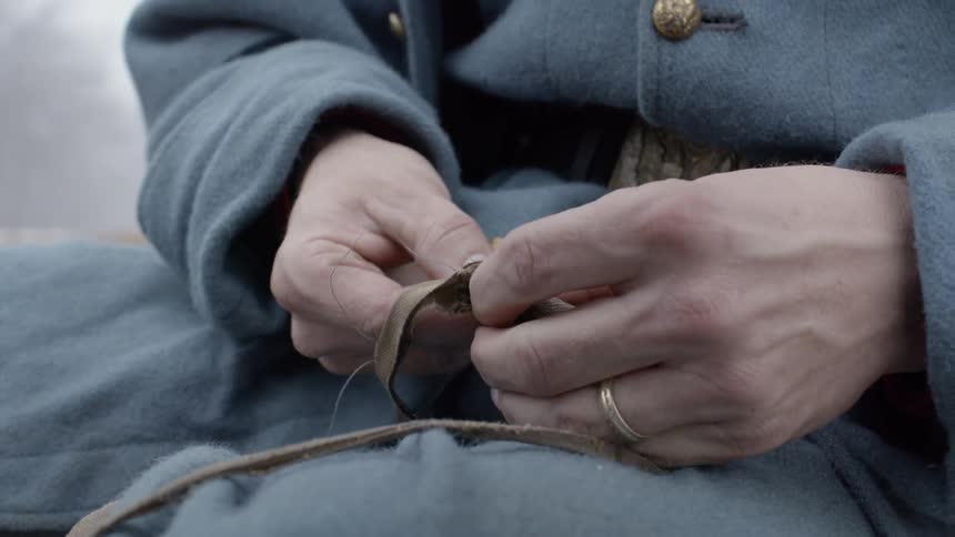 A man is threading some fabric in his hands