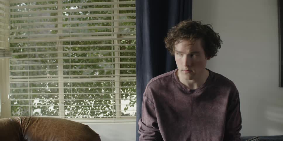 A man sitting near a window looks up
