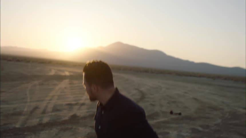 Man walking over an empty field at sunset