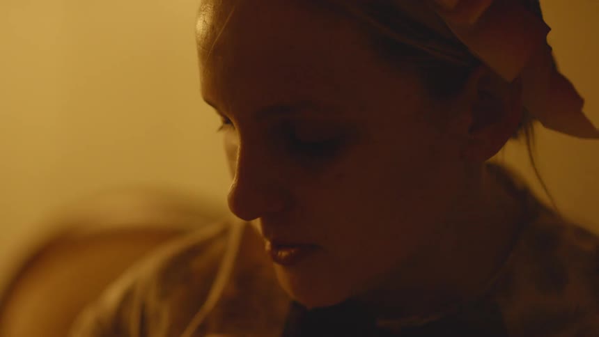 A woman is looking down talking in the dark room