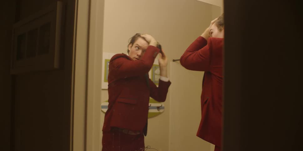 A man combs his hair and leaves the restroom