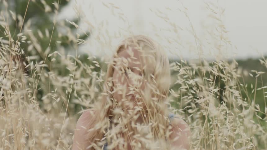 The woman sits still in the tall grass