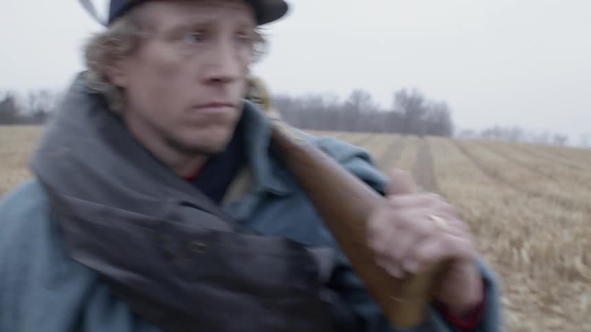 Civil war reenactor walks across a field