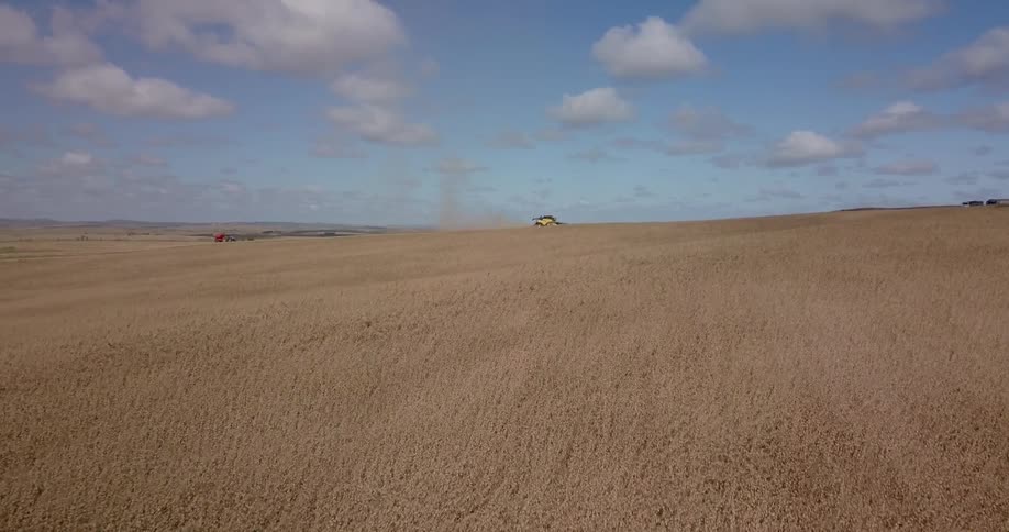 Tractor drives over dusty plains on a clear day