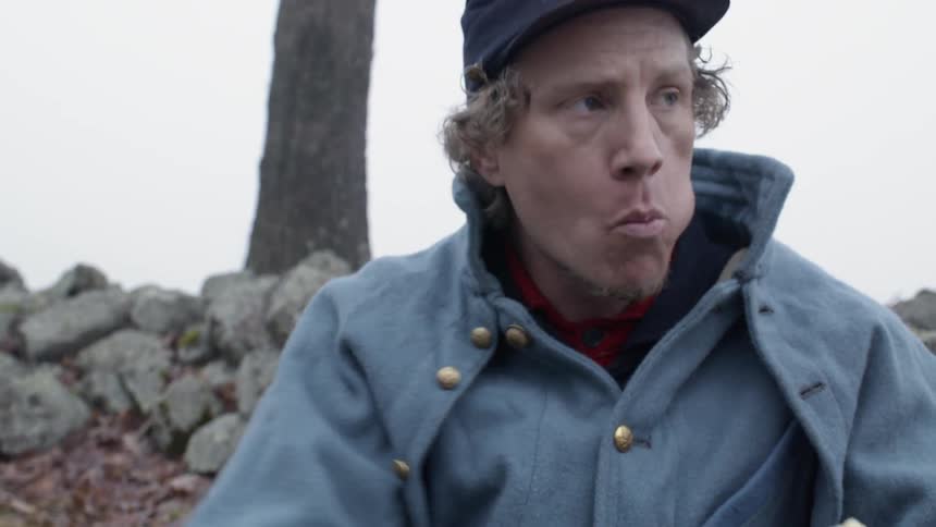 Man eats a sandwich as he sits near a tree