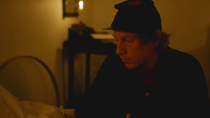 Man sits in a dim room looking down