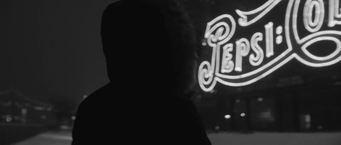 Person standing outside near a large neon sign