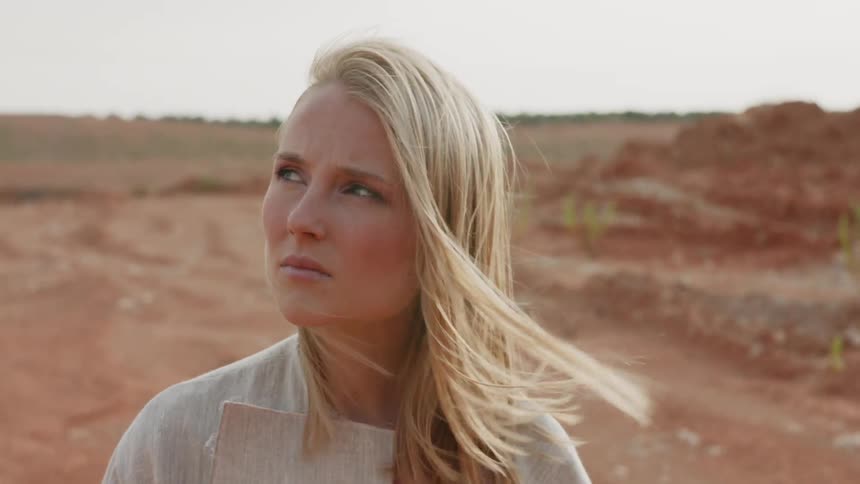 Blond woman looks around as the wind blows her hair