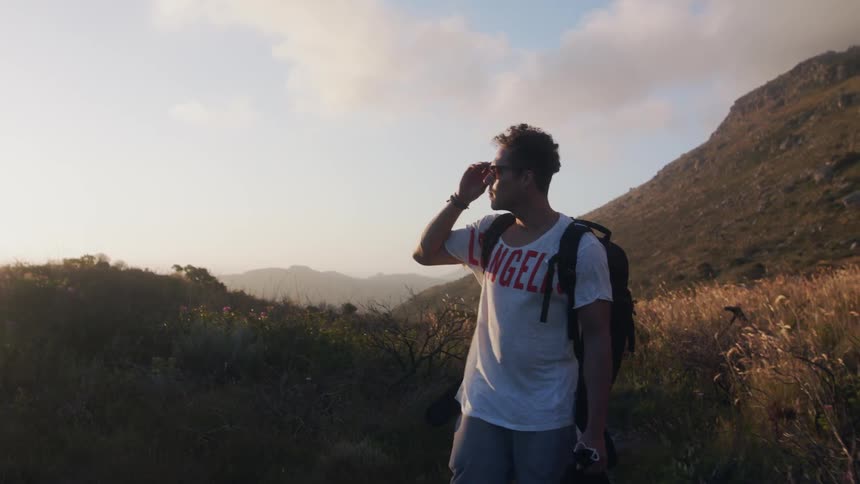 Backpacker walks along mountain path gazing at scenery