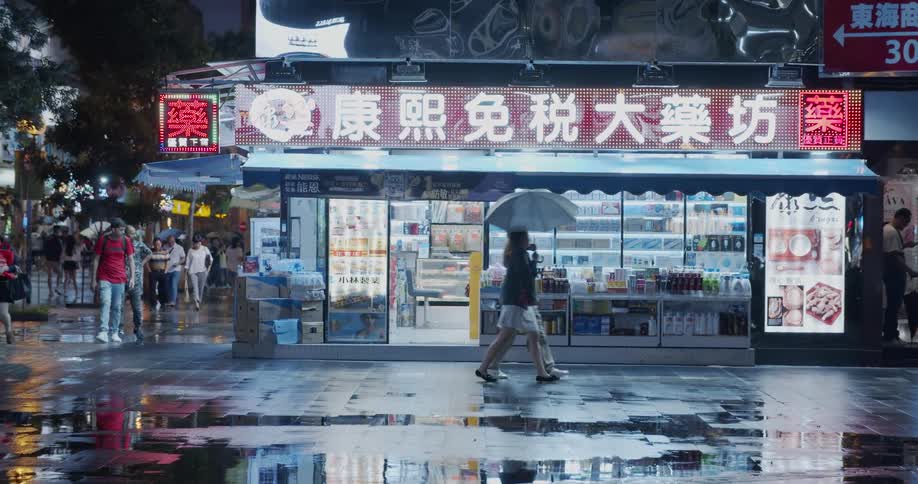 Pedestrians are walking in a shopping district on a rainy night in an asian city