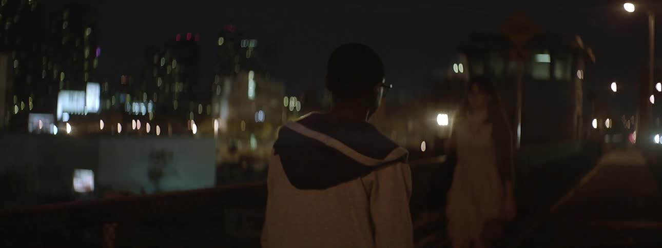 Man walks down a city street towards blinking light