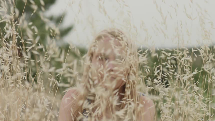A blond woman sits in the tall grass