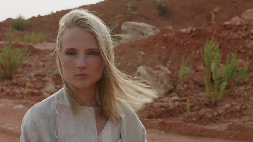 Blond woman blinks as the wind blows her hair