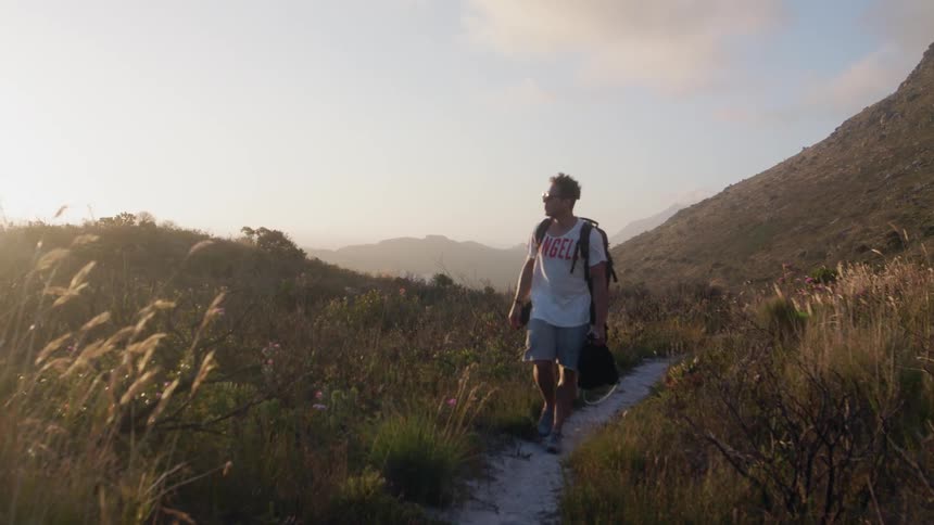 A man is hiking down a small trail
