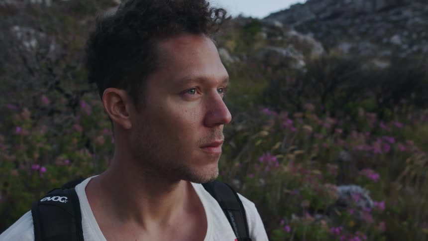 A man stands on a hillside as the wind blows