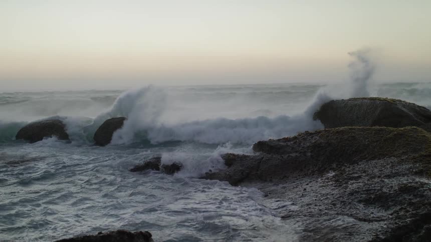 Ocean waves crash and splash against the rocks on a windy day