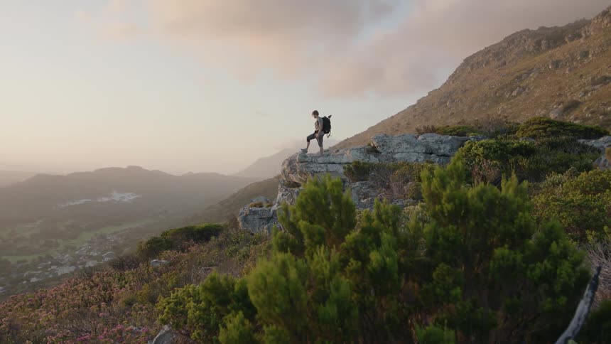 Hiker stands in mountains at sunset