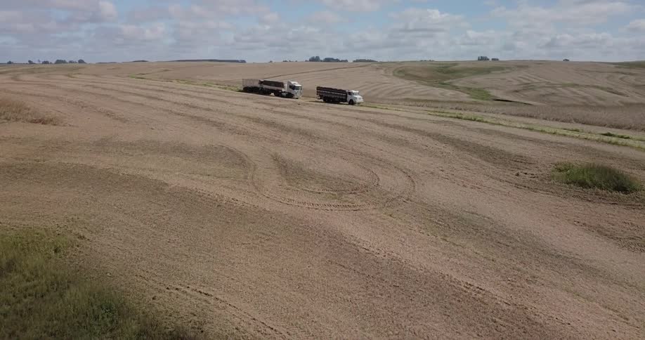 Tractor rolls across sandy land creating dust