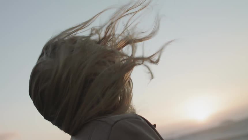 A woman's blonde hair is blown by the wind