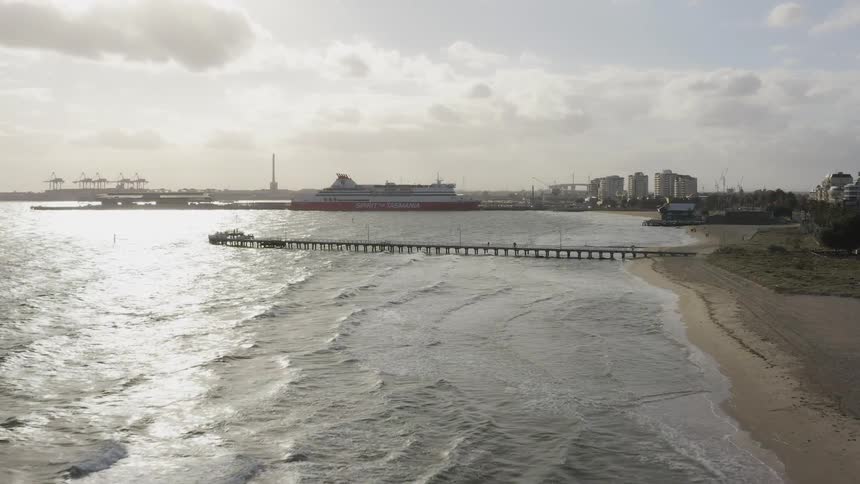 A dock extends out into the ocean from the beach