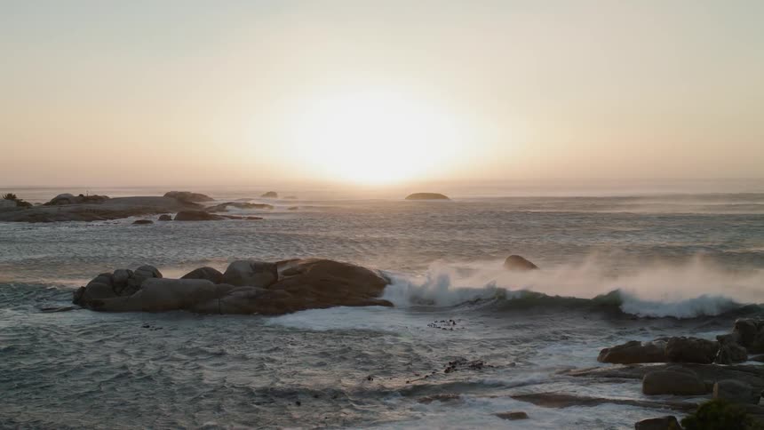 Ocean waves splash against the rocks at sunset