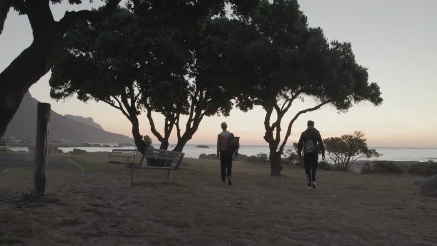 Two people walk on a beach at sunset