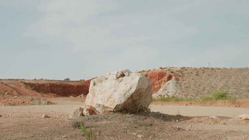 A person is sitting on top of the large white stone