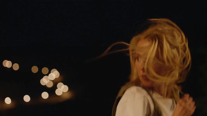 Woman jogs outside at night looking behind