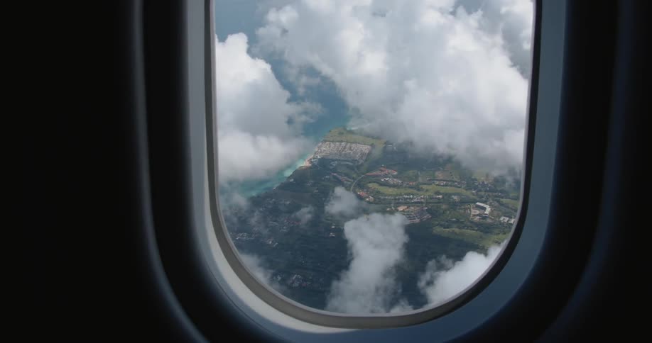 The plane flies high over the green fields